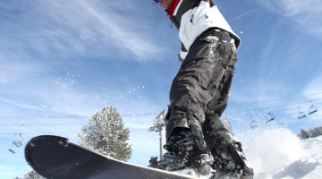 SNowboarder på vej ud over bakke med blå himmel i baggrunden