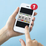 kvinde-holder-smartphone-i-haenderne-og-spiller-paa-slot-machine